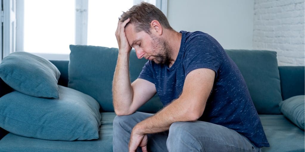 A man enduring a depressive epsiode, holding his head.