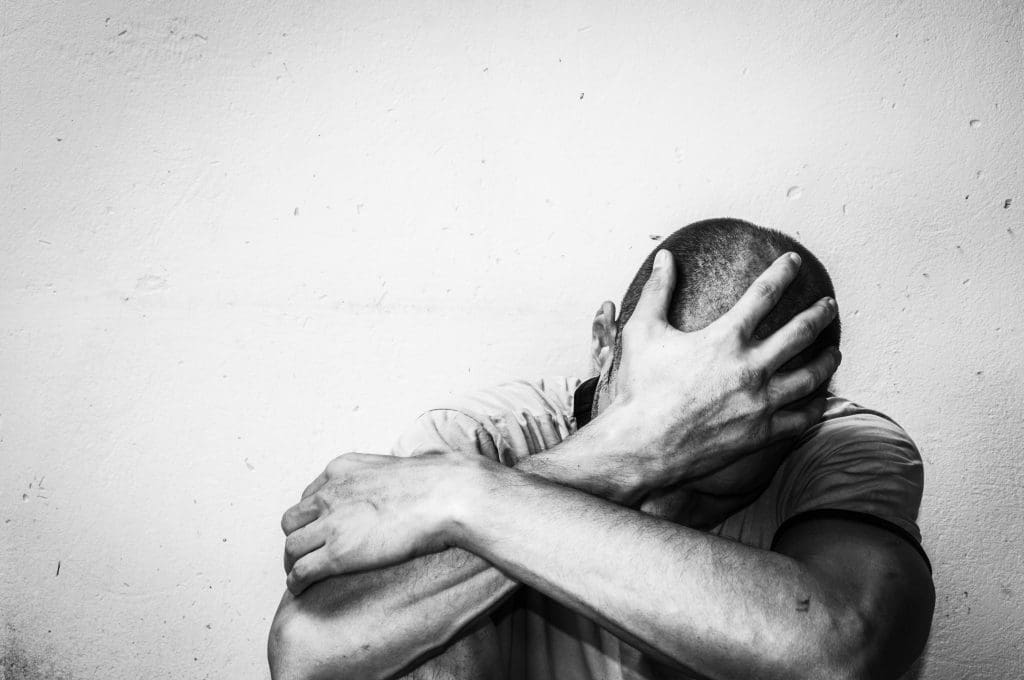 A man, feeling passively suicidal, holding his head in his hands.