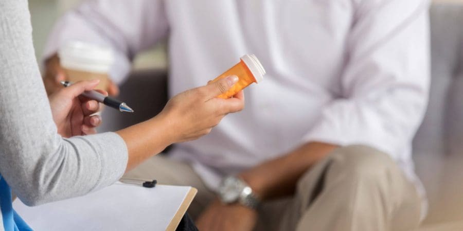 Doctor holding prescription drug in front of the patient